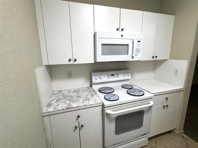 a kitchen with white cabinets and white appliances