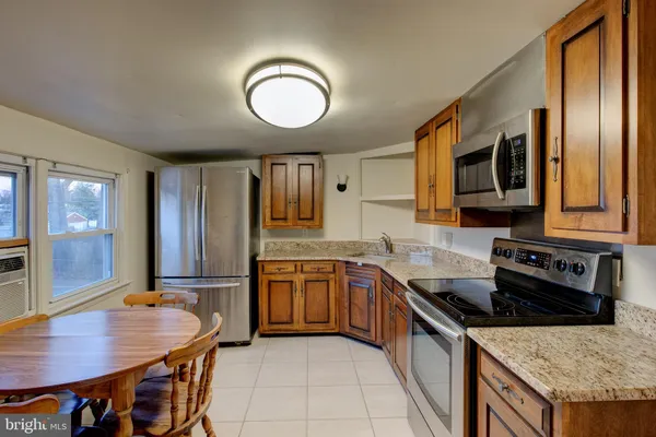 a kitchen with stainless steel appliances granite countertop a stove top oven a sink dishwasher a dining table and chairs with wooden floor