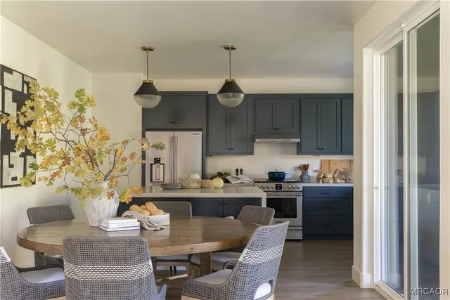 a kitchen with stainless steel appliances granite countertop a stove a sink dishwasher a dining table and chairs with wooden floor