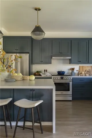 a kitchen with stainless steel appliances a stove a sink island and wooden cabinets