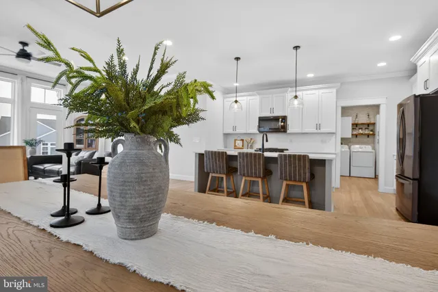 a kitchen with stainless steel appliances kitchen island granite countertop a refrigerator a stove a sink a dining table and chairs with wooden floor