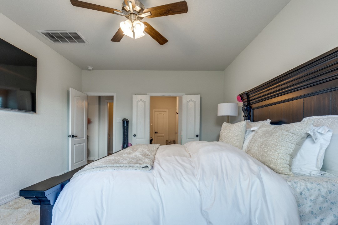 8327 Calico Pennant Way Fulshear, TX 77441 - Photo 21 of 44 a bedroom with a bed and a chandelier