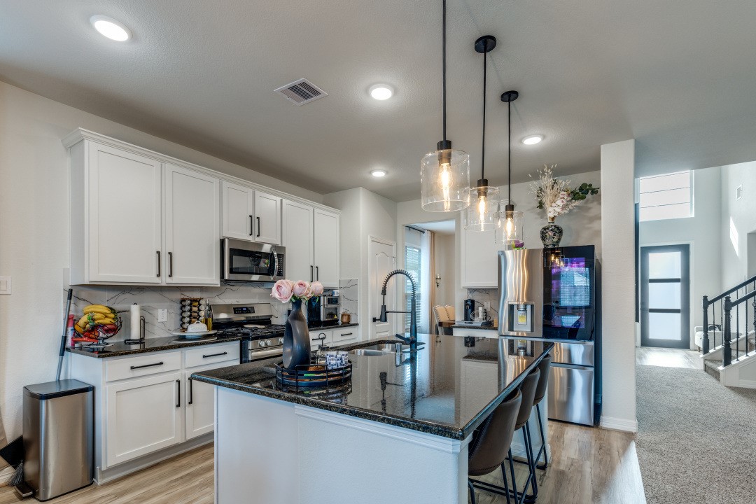 8327 Calico Pennant Way Fulshear, TX 77441 - Photo 7 of 44 a kitchen with stainless steel appliances granite countertop a sink a stove and a refrigerator