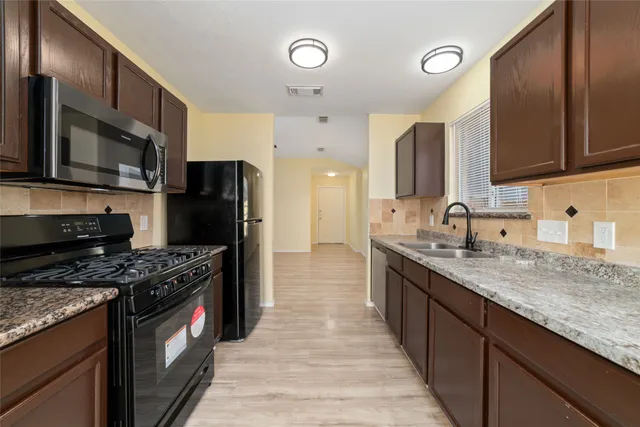 a kitchen with stainless steel appliances granite countertop a stove a sink and a refrigerator