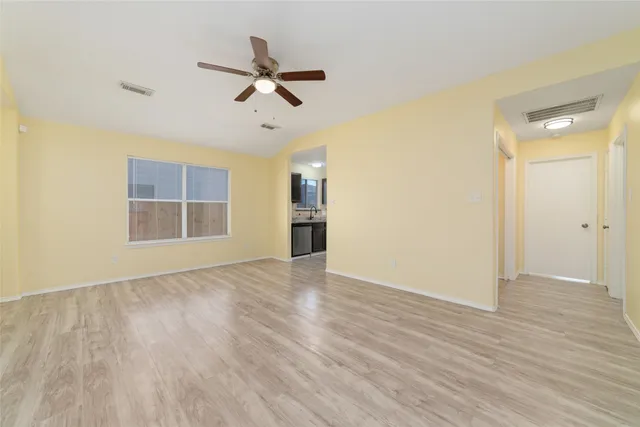 a view of empty room with wooden floor and ceiling fan
