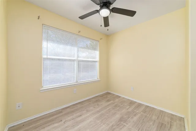 an empty room with a window and a ceiling fan