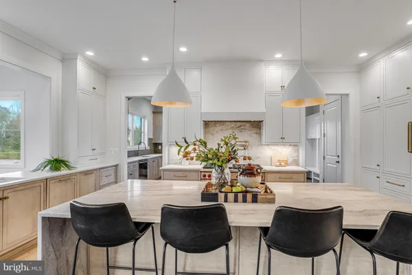 a kitchen with stainless steel appliances kitchen island granite countertop a dining table chairs and a refrigerator