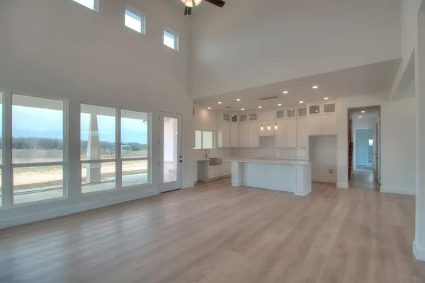 a view of an empty room with wooden floor and a kitchen