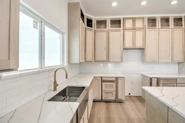 a large white kitchen with a large window a sink and cabinets