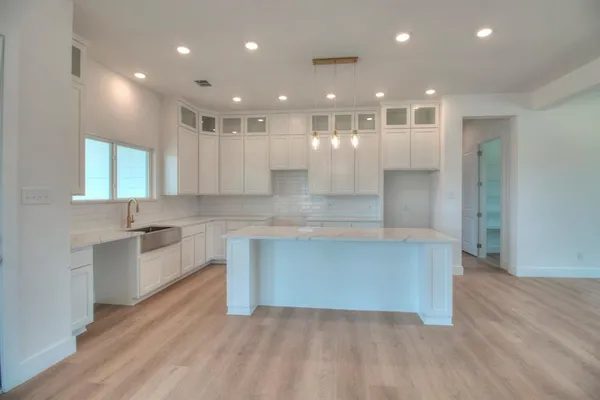 a large kitchen with stainless steel appliances kitchen island a large counter top and a wooden floors