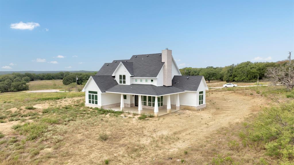117 Mustang Springs Circle Sunset, TX 76270 - Photo 36 of 40 Back of property with a patio area, roof with shingles, driveway, and a chimney