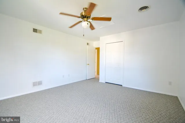 an empty room with windows and fan
