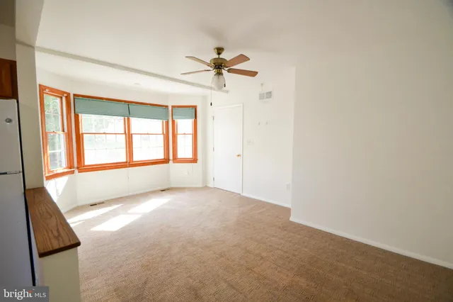 an empty room with windows and fan