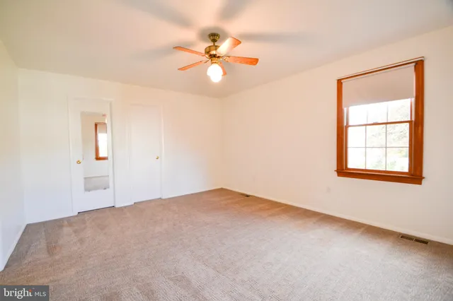 an empty room with windows and fan