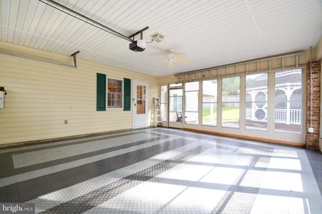 a view of an empty room with a window and chandelier fan