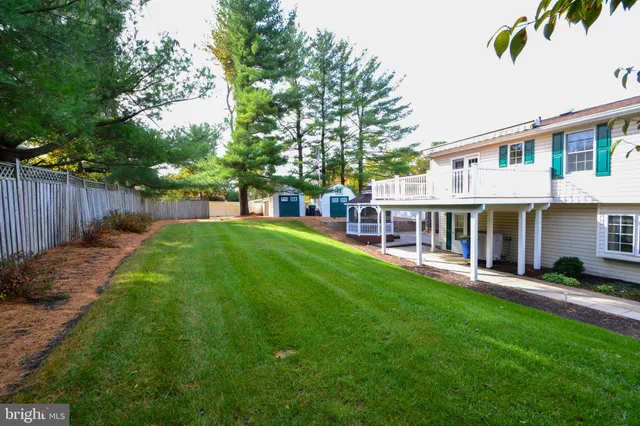 a view of a house with a yard and large trees