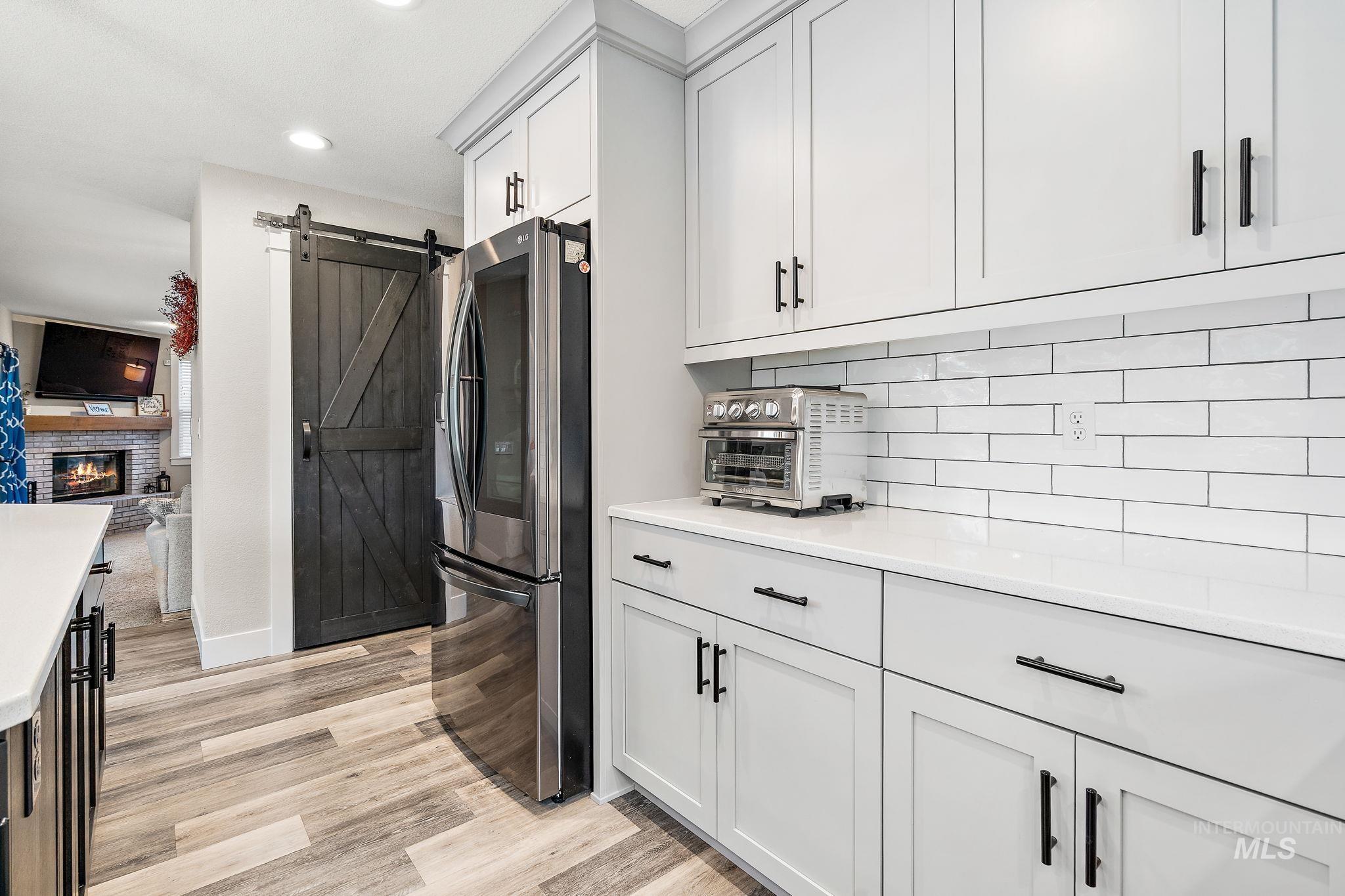 5363 North Hickory Run Place Boise, ID 83713 - Photo 12 of 50 Kitchen with a barn door, smart refrigerator, light wood finished floors, light stone countertops, and recessed lighting