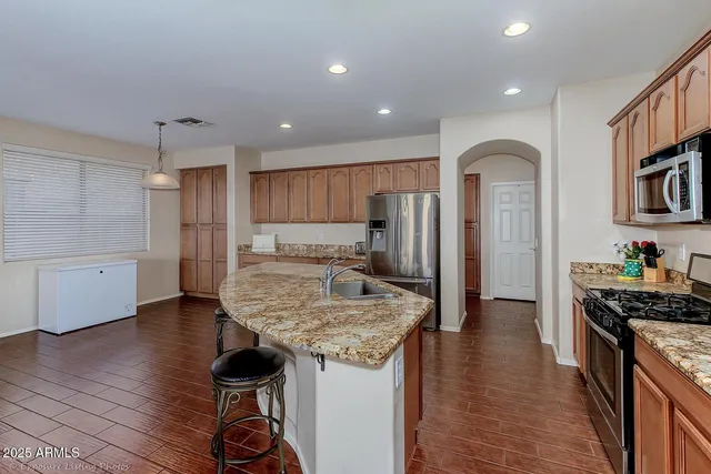 a kitchen with stainless steel appliances granite countertop a refrigerator and a stove top oven