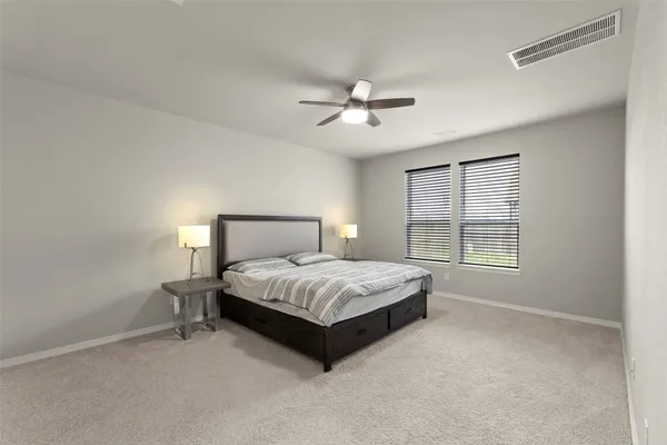 a spacious bedroom with a bed lamp and a window