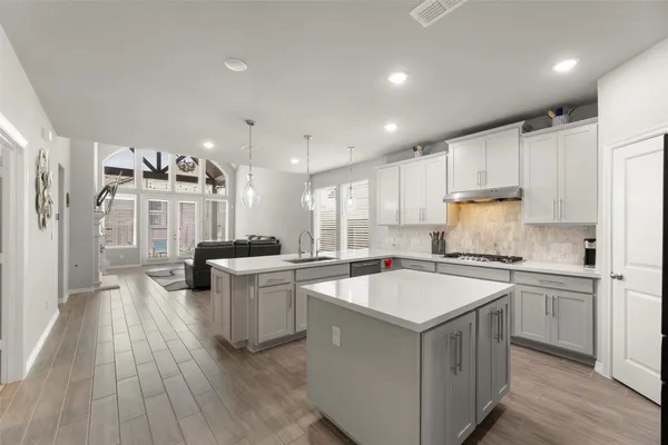 a kitchen with a stove a sink a refrigerator and white cabinets with wooden floor