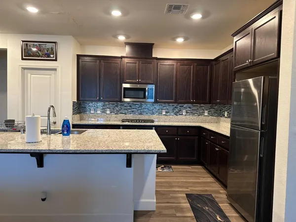 a kitchen with kitchen island granite countertop wooden cabinets a refrigerator stove a sink and dishwasher