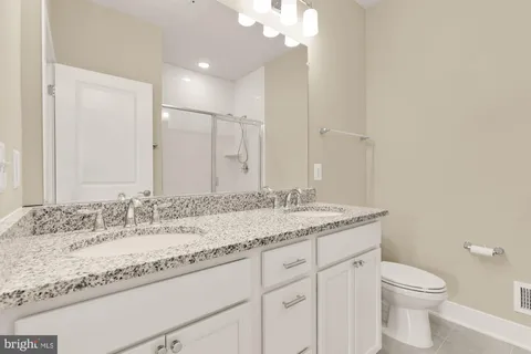 a bathroom with a granite countertop sink a toilet and a mirror