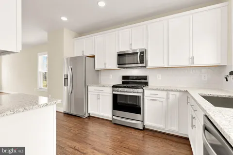a kitchen with stainless steel appliances granite countertop a refrigerator stove and white cabinets