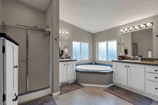 a bathroom with a granite countertop bathtub sink vanity mirror and toilet