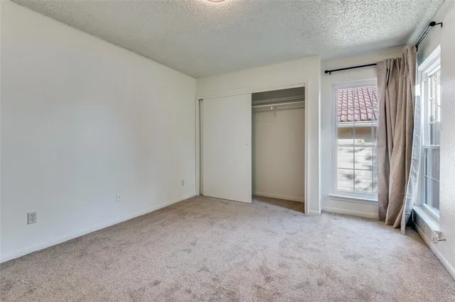 an empty room with chandelier fan and windows