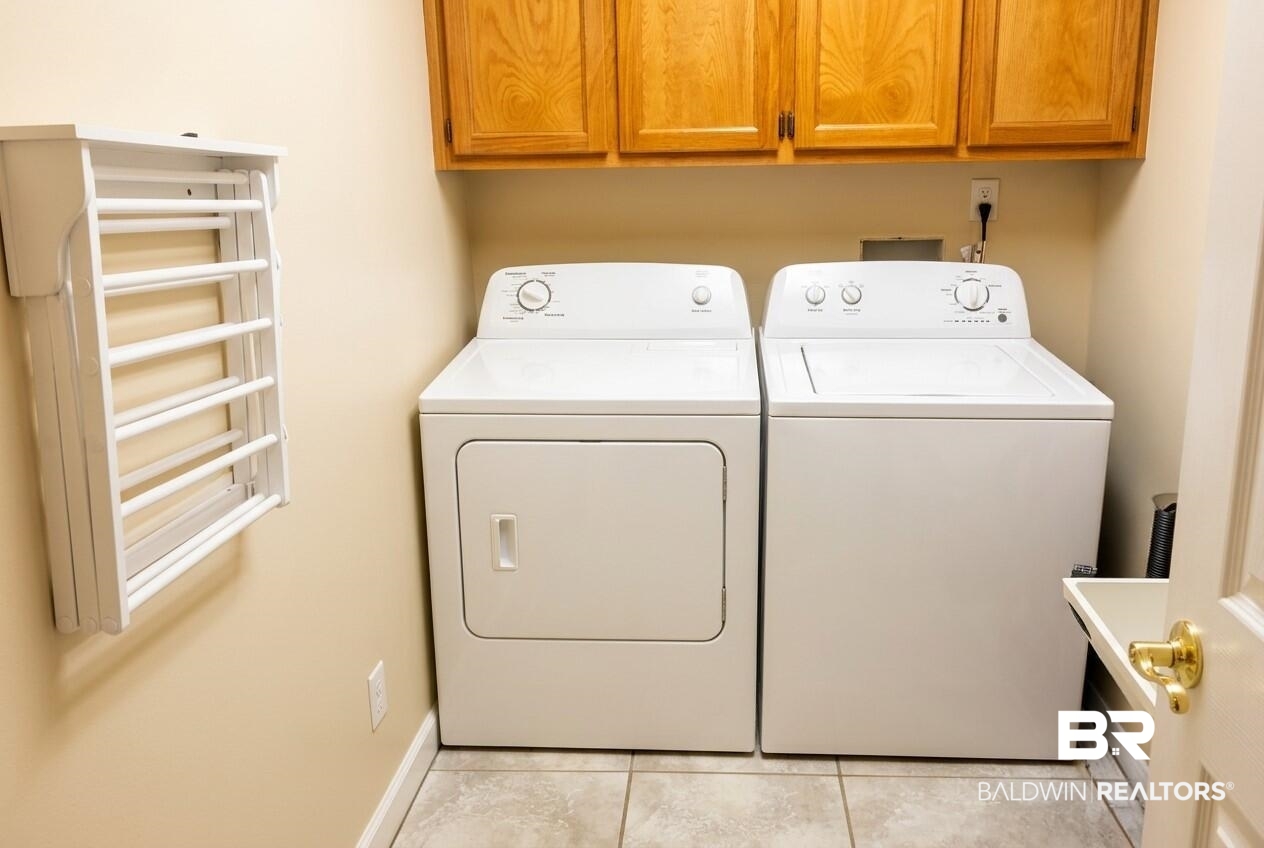 8008 Patricks Landing Road Bay Minette, AL 36507 - Photo 26 of 33 Laundry room featuring wood-finish cabinetry, tile flooring, and wall-mounted drying rack