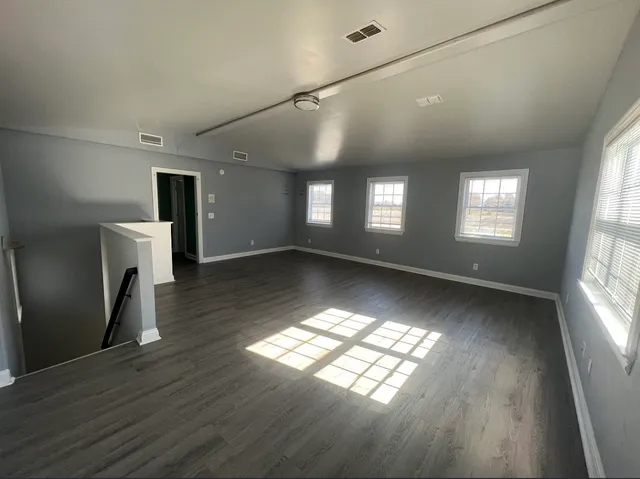 a view of an empty room with window and wooden floor