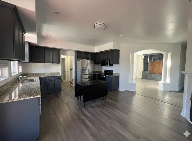 a large kitchen with a center island wooden floor stainless steel appliances and cabinets