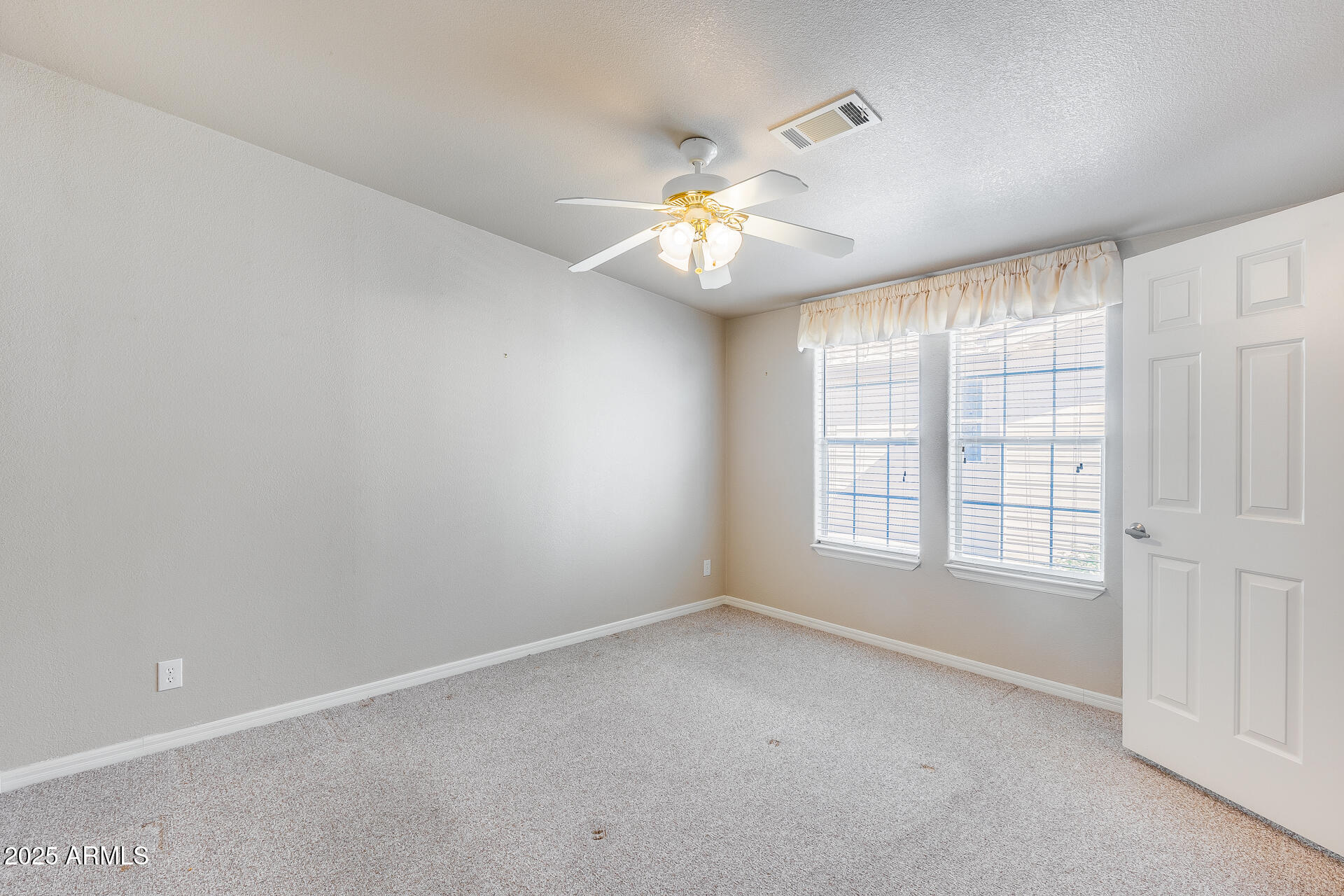 3301 South Goldfield Road, Unit 1043 Apache Junction, AZ 85119 - Photo 17 of 36 an empty room with chandelier fan and windows