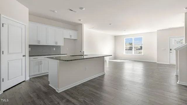 a kitchen with granite countertop white cabinets and wooden floor