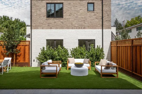 a view of a patio with couches chairs potted plants and wooden fence