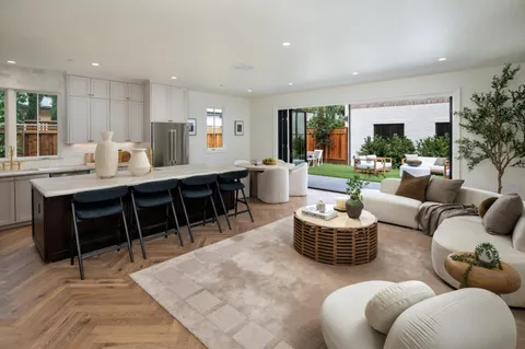 a living room with furniture kitchen view and a large window