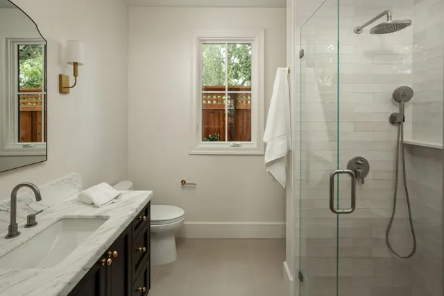 a bathroom with a granite countertop sink a toilet and shower