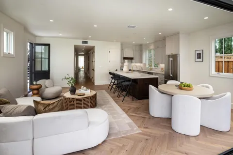 a living room with furniture a wooden floor and kitchen view