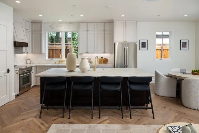 a kitchen with stainless steel appliances granite countertop a table chairs sink refrigerator and microwave