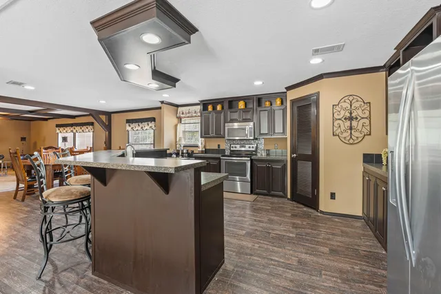 a kitchen with stainless steel appliances granite countertop a refrigerator a sink and a stove top oven