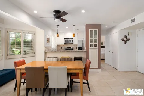 a dining room with stainless steel appliances kitchen island granite countertop a dining table chairs and a refrigerator