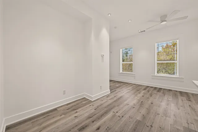 an empty room with wooden floor and windows
