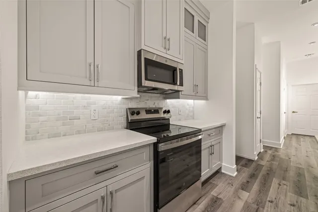 a kitchen with stainless steel appliances granite countertop a stove a microwave and a white cabinets
