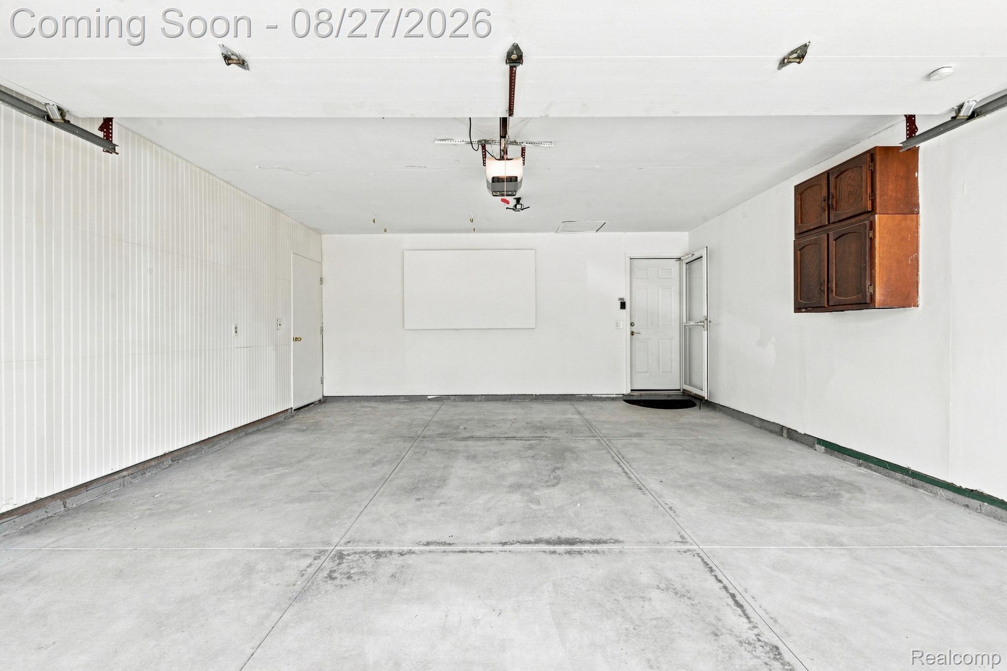42120 Ridge Road West Novi, MI 48375 - Photo 31 of 32 Spacious garage with concrete flooring, white painted walls, storage cabinetry, and side entry door