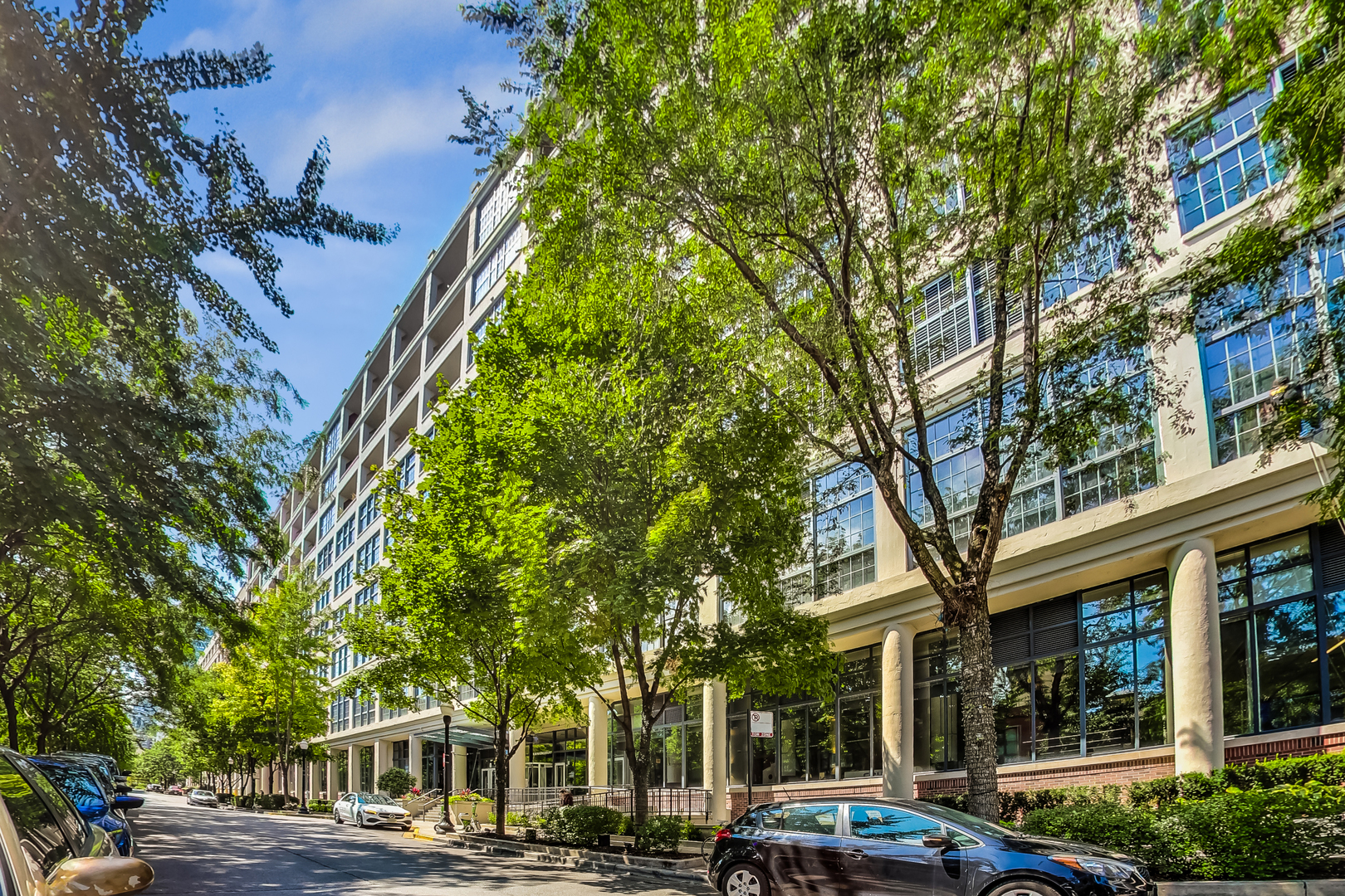 a front view of a building with lots of trees and plants