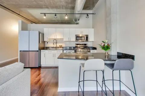 a kitchen with stainless steel appliances granite countertop a refrigerator a stove a sink a dining table and chairs