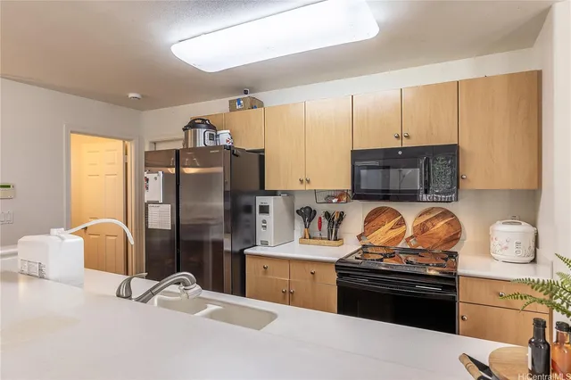 a kitchen with stainless steel appliances kitchen island granite countertop a refrigerator stove and sink