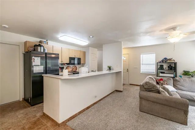 a living room with furniture a chandelier and kitchen view