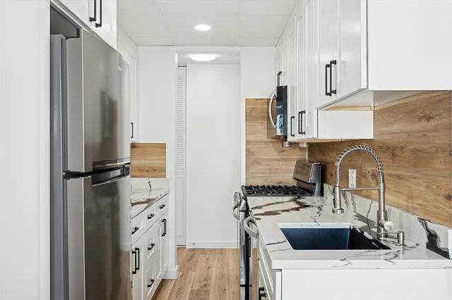 a kitchen with stainless steel appliances a sink and a refrigerator