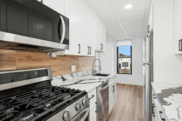 a kitchen with a stove a sink and wooden floor